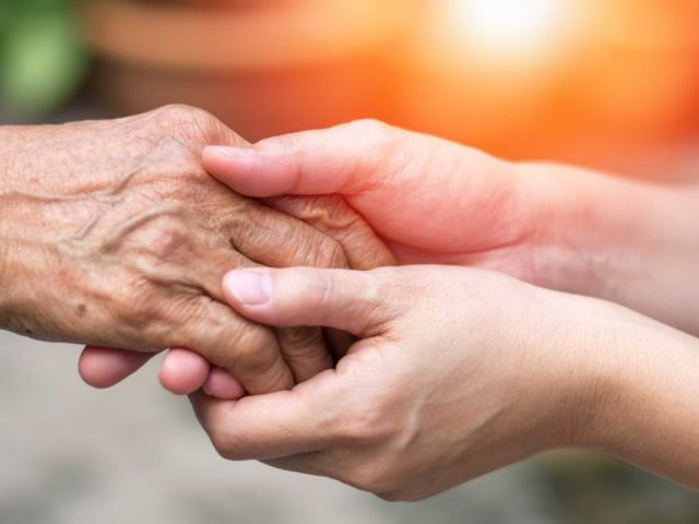Younger person holding the hand of an elder